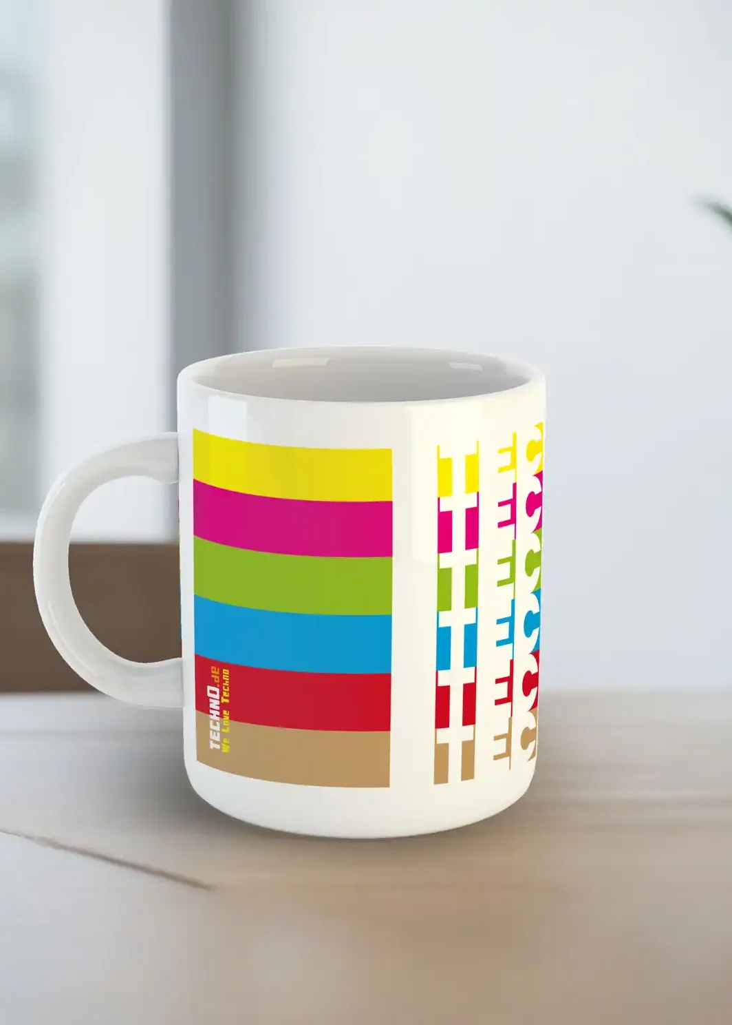 Eine Tasse von der Seite mit dem Text Techno in verschiedenen Farben